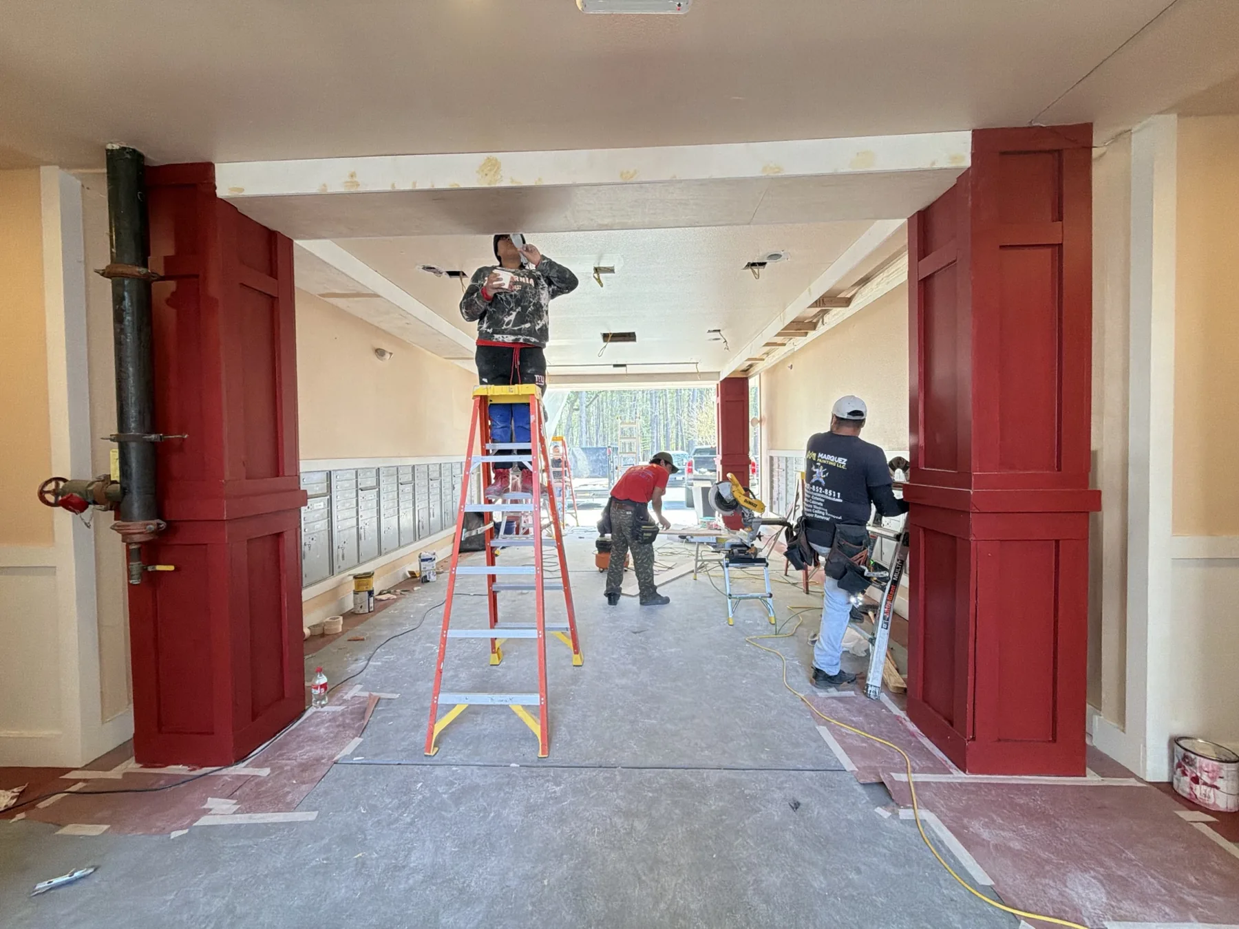 Apartment corridor update with red columns, ladders, and active crew work